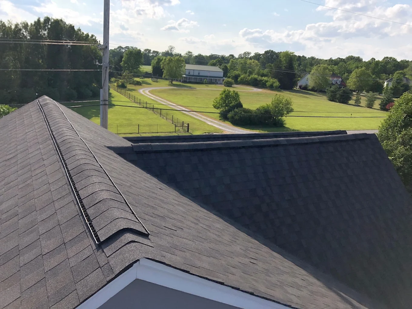 A completed shingle roof with ridge vent on a large property