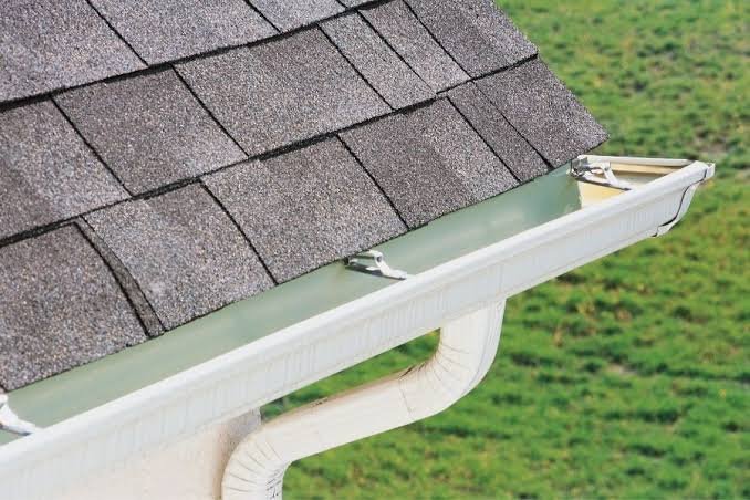 A seamless gutter and downspout fitted along a shingle roofline