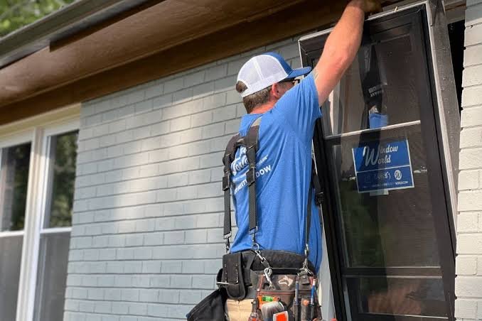 An installer fitting a replacement window on a brick home